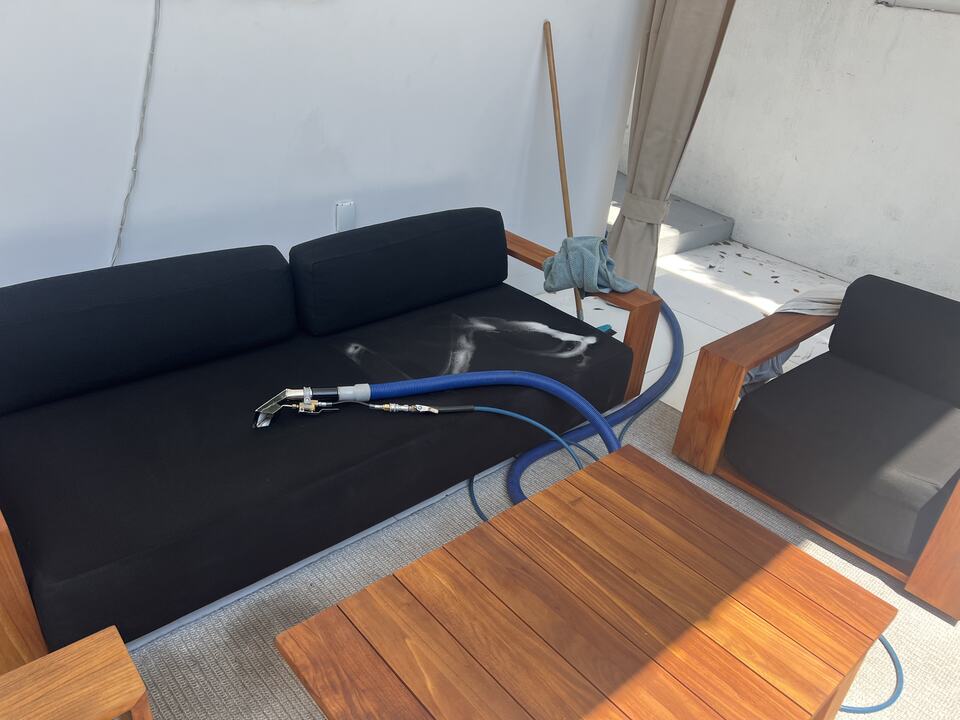 An upholstery-cleaning tool resting on a dark sofa