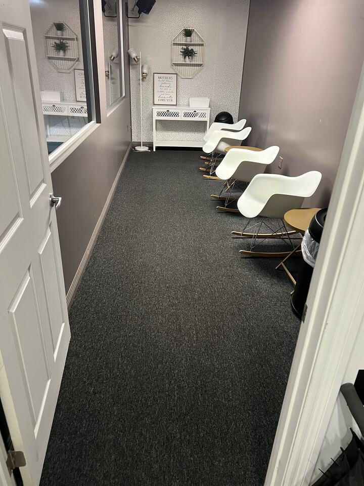 Carpeted waiting area with a row of chairs